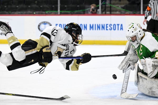 Andover forward Isa Goettl (12) leaps into her shot as she was tripped up against Edina goaltender Uma Corniea (41) during the first period of a Class