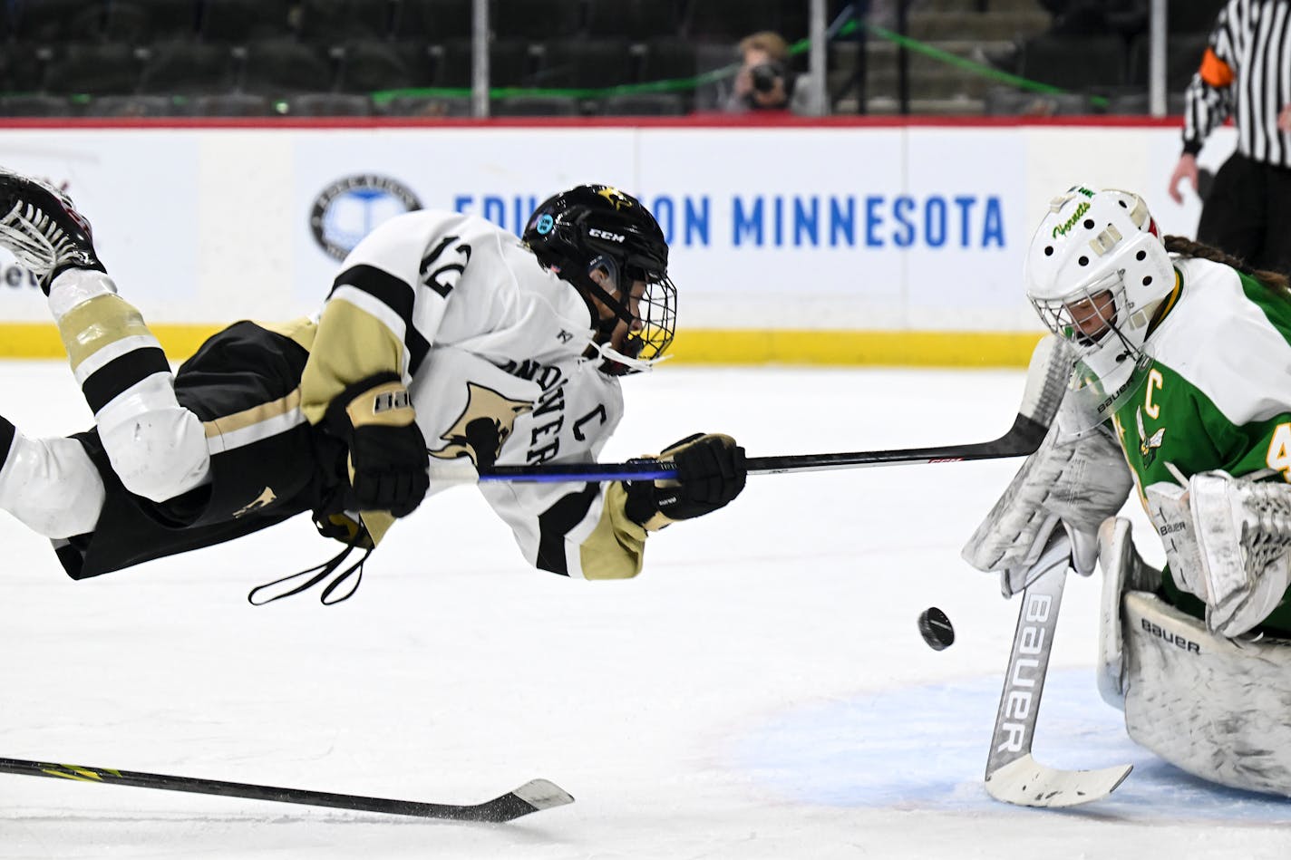 Andover forward Isa Goettl (12) leaps into her shot as she was tripped up against Edina goaltender Uma Corniea (41) during the first period of a Class 2A girls' hockey state tournament semifinal game Friday, Feb. 24, 2023 at the Xcel Energy Center in St. Paul, Minn.. ] AARON LAVINSKY • aaron.lavinsky@startribune.com