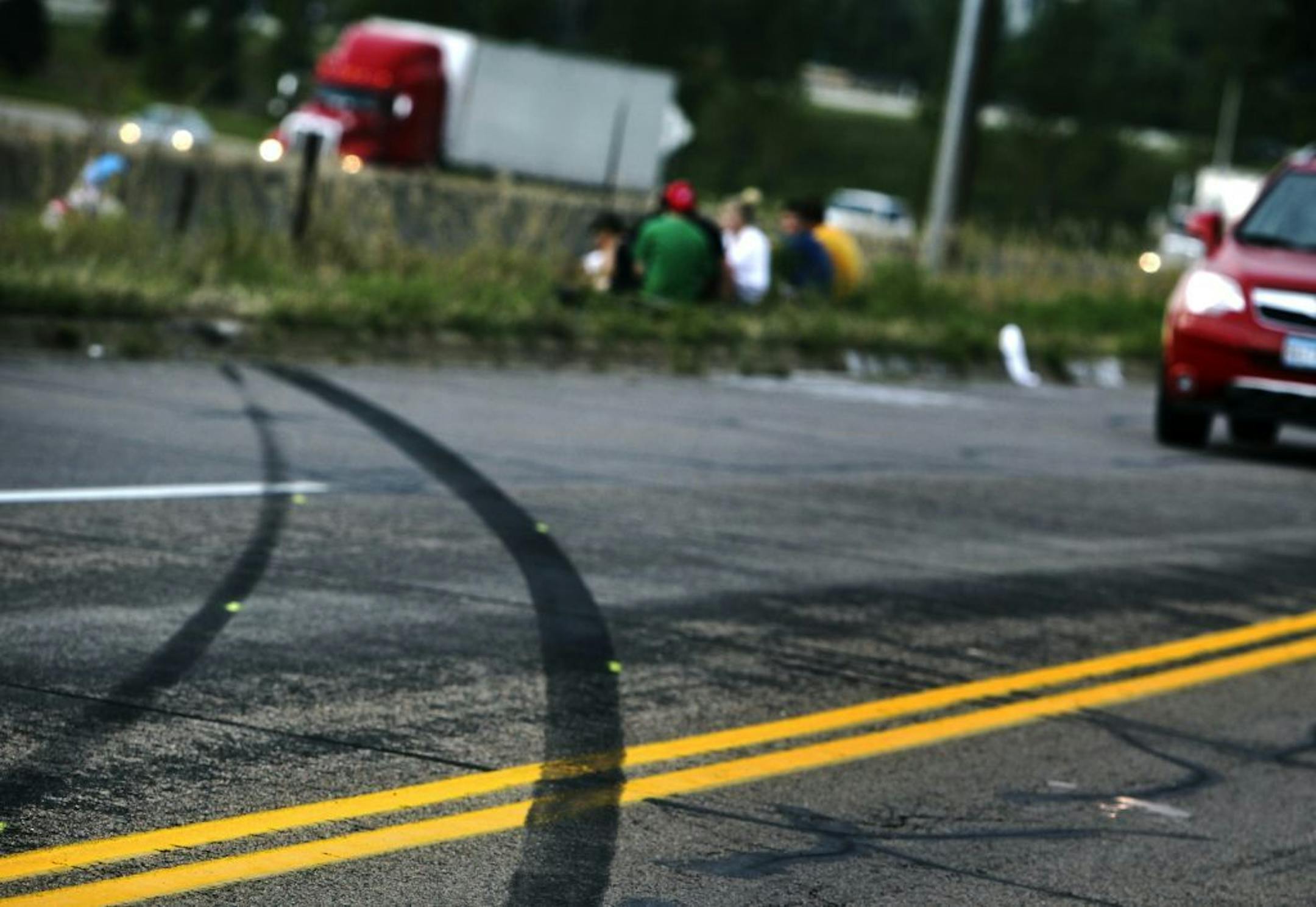 Tire skid marks are visible off of Buck Hill Road where classmates and friends of Frederick J. Alexander, 16, of Burnsville, and Alesha K. Roehl, 17, of Northfield, who were killed in a car accident Tuesday afternoon after the car five of them were riding in sped off a Burnsville frontage road, rolled over and wound up on Interstate 35, gathered near the crash site Wednesday, August 22, 2012, in Burnsville, MN.