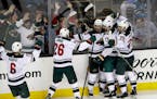 Minnesota Wild's Nino Niederreiter (22), center, is mobbed by teammates after his game-winning goal during overtime of an NHL hockey game against the 