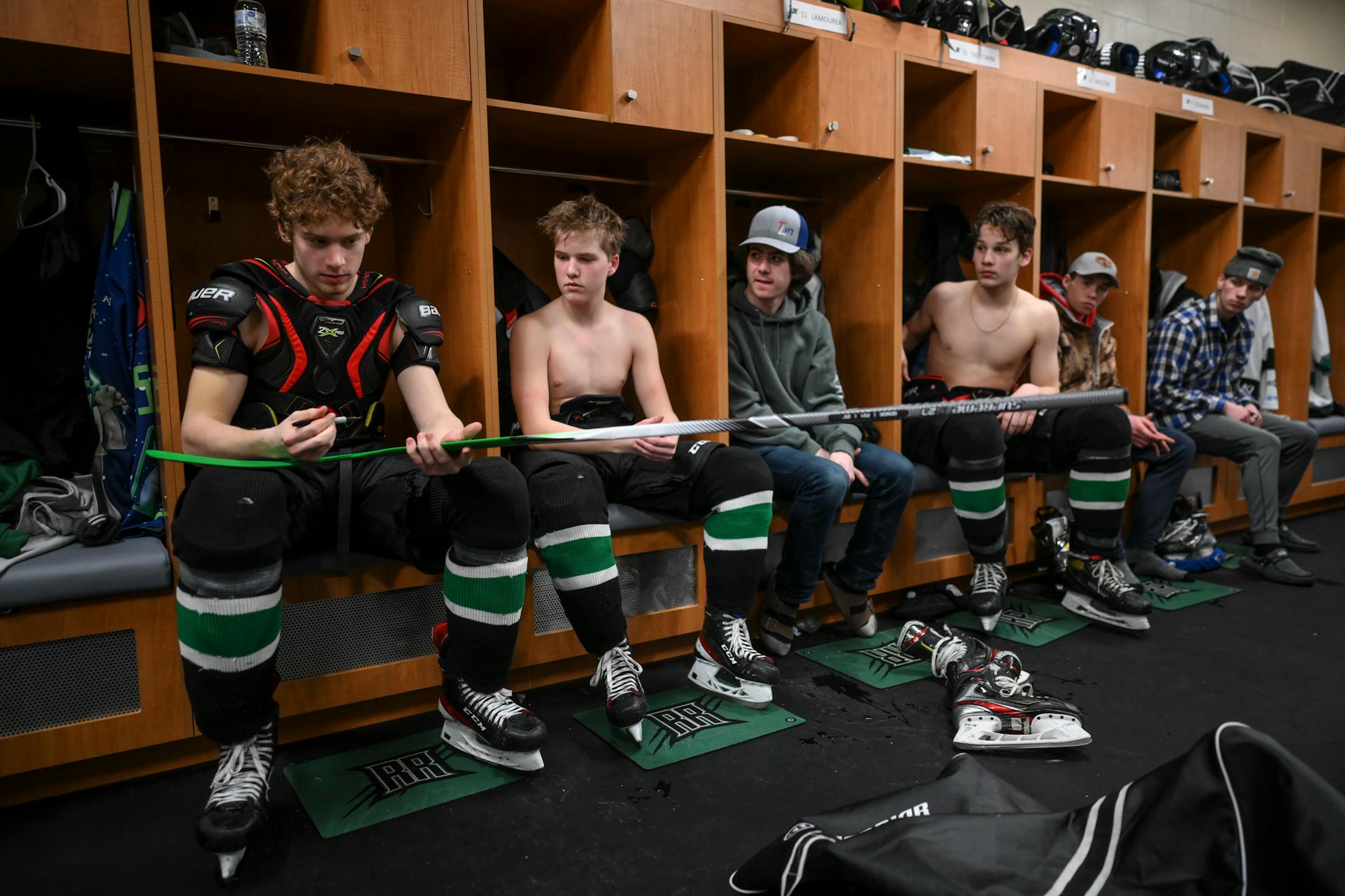 Rock Ridge players, including Nick Troutwine, left, of Eveleth, took turns signing a goalie stick, writing who they're playing for as they head toward a possible post-season run Tuesday, Feb. 22, 2022.