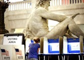 With the Father of Waters sculpture looming to her rear, Kym Spotts of Minneapolis completes her absentee ballot at the Minneapolis City Hall Friday, 