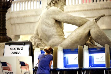 With the Father of Waters sculpture looming to her rear, Kym Spotts of Minneapolis completes her absentee ballot at the Minneapolis City Hall Friday, 