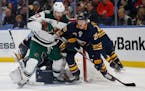 Buffalo Sabres defenseman Rasmus Dahlin, right, and Minnesota Wild forward Marcus Foligno, left, battle for the puck during the second period of an NH