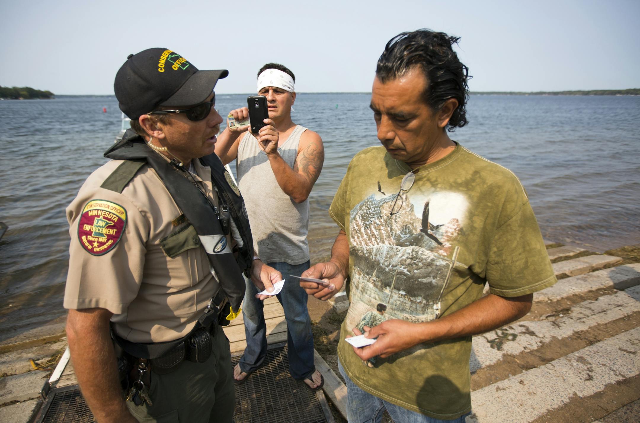 DNR conservation officer Tim Collette gives a citation to Jim Northrup (right) and Todd Thompson, (left) for Taking Fish by Illegal Methods for setting a gill net on Gull Lake Friday morning.