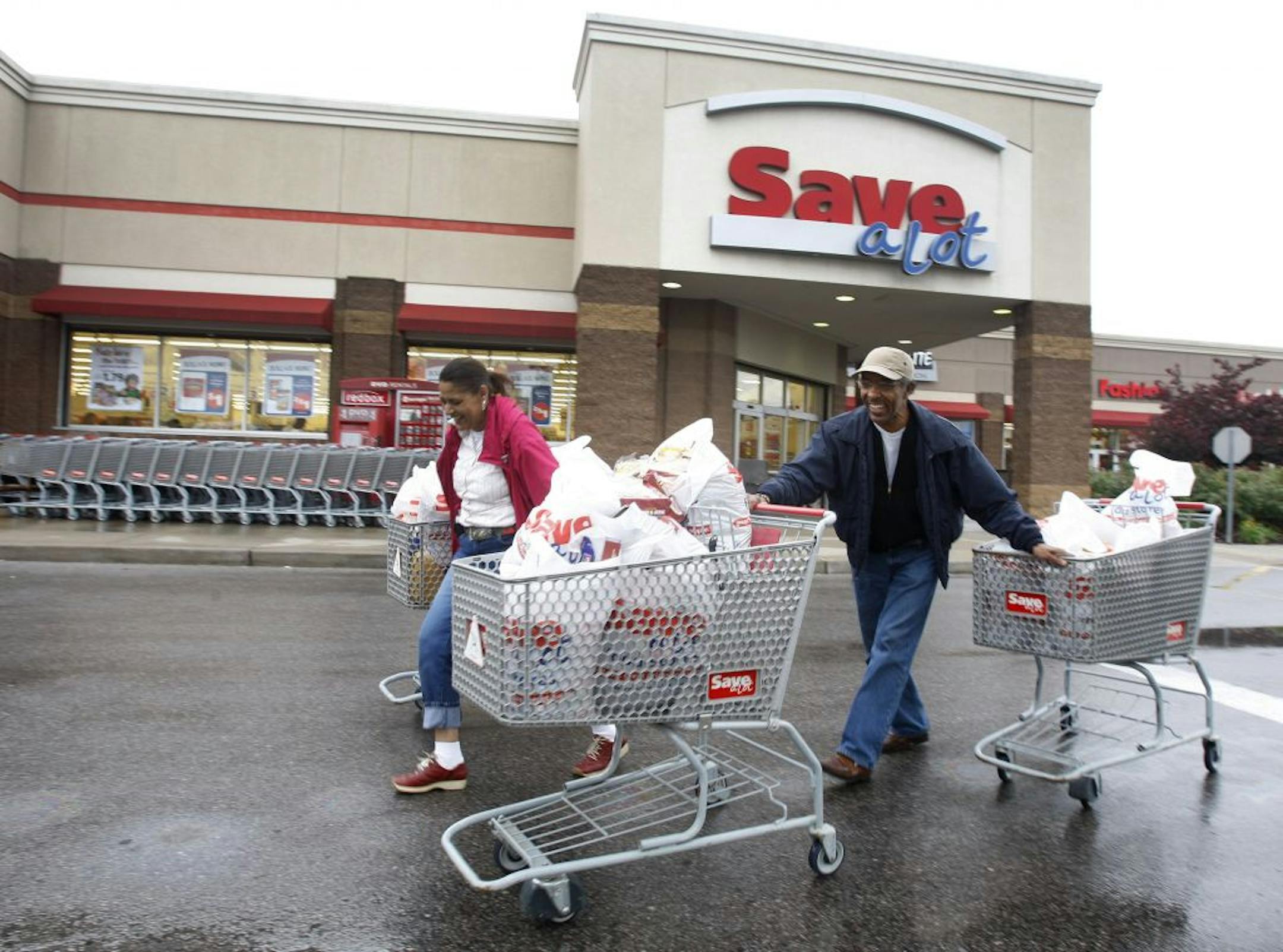 Shoppers Camelious Thompson and her brother Mark Eaton leave a Save-A-Lot store in St. Louis, Missouri, U.S., on Thursday, May 20, 2010. Supervalu Inc.'s Save-A-Lot unit, a discount grocer specializing in store-brand products, plans to expand in urban areas to fill in gaps left after larger chains moved to the suburbs. Photographer: Peter Newcomb/Bloomberg Camelious Thompson; Mark Eaton