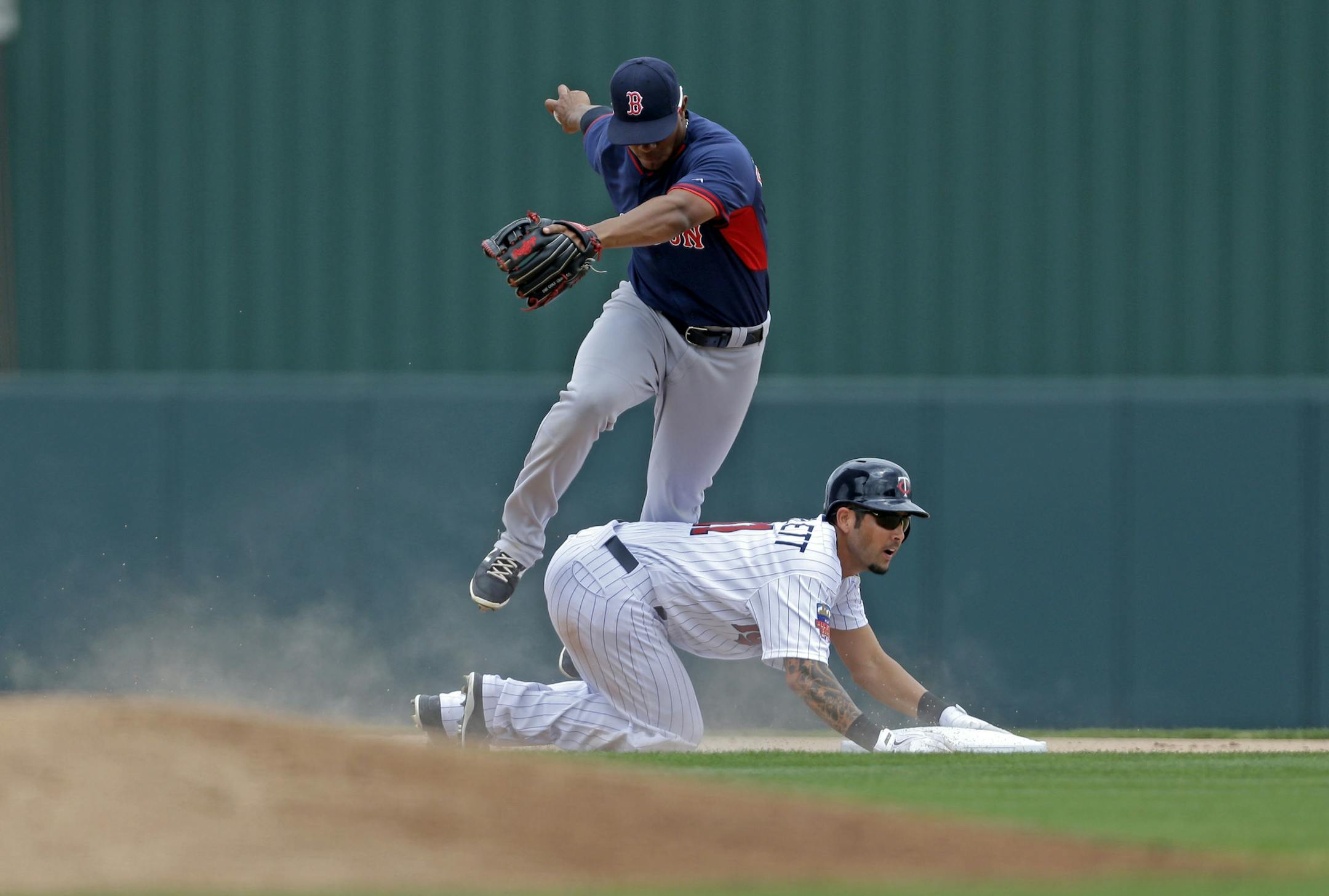 Minnesota Twins Jason Bartlett is forced at second but breaks up the double play off the bat of first baseman Joe Mauer (7), as Boston Red Sox shortstop Xander Bogaerts trips over him with the ball in the first inning of an exhibition baseball game in Fort Myers, Fla., Friday, March 28, 2014. (AP Photo/Gerald Herbert)
