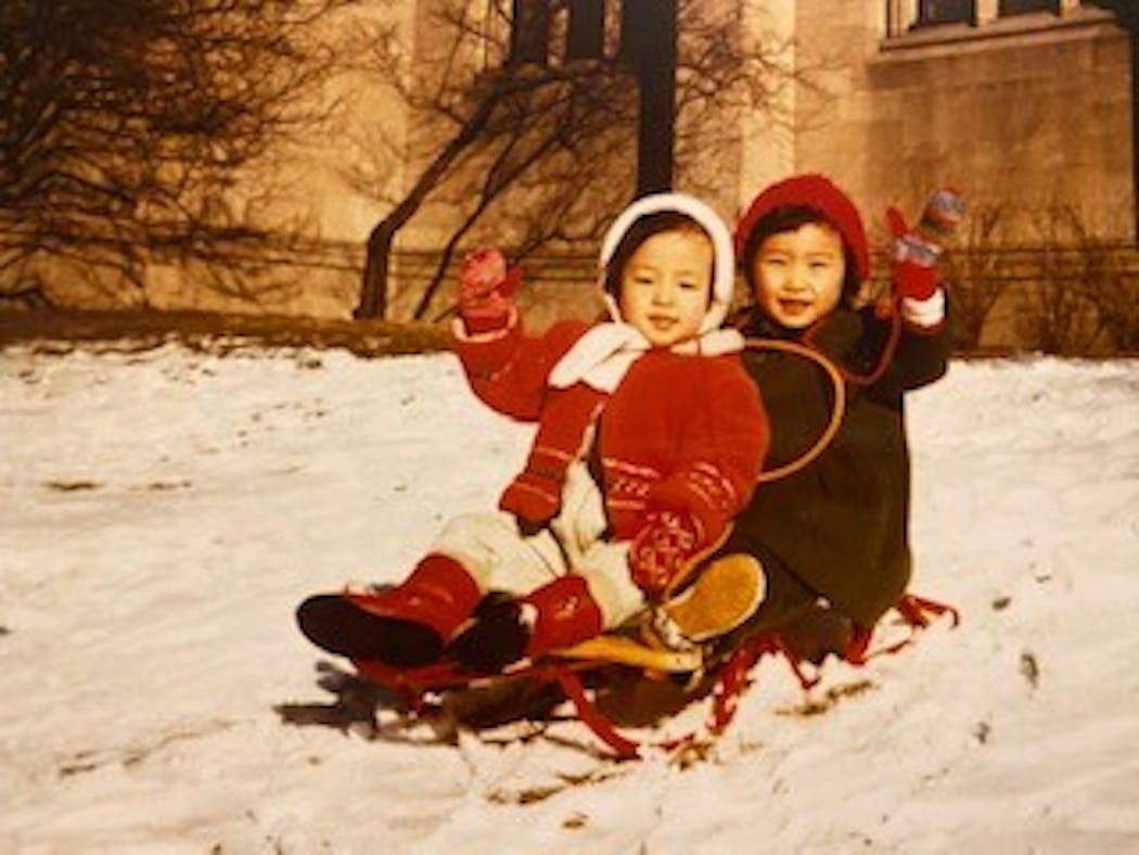 Sisters Martha and Mary Ha waved to the camera from a sled from their childhood.