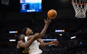 The Wolves' Anthony Edwards drives to the rim, with Golden State's Draymond Green intervening and getting called for a foul.