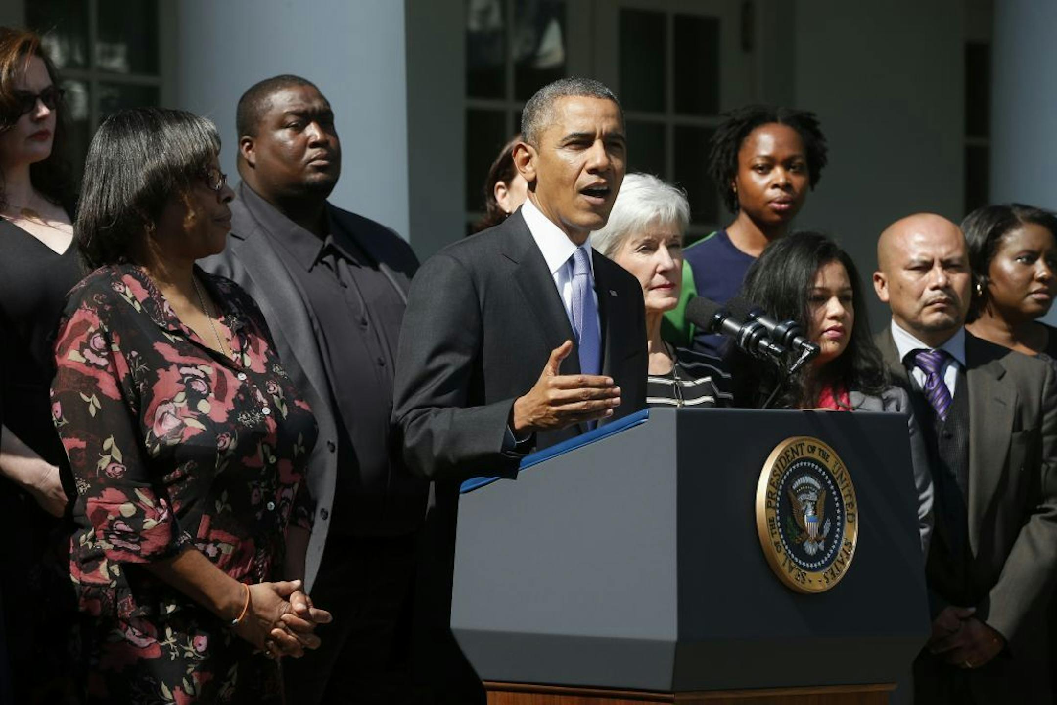 President Barack Obama, accompanied by Health and Human Services Secretary Kathleen Sebelius, and people who support the Affordable Care Act, his signature health care law, speaks in the Rose Garden of the White House in Washington, Tuesday, Oct. 1, 2013. Congress plunged the nation into a partial government shutdown Tuesday as a long-running dispute over President Barack Obama's health care law forced about 800,000 federal workers off the job, suspending all but essential services.