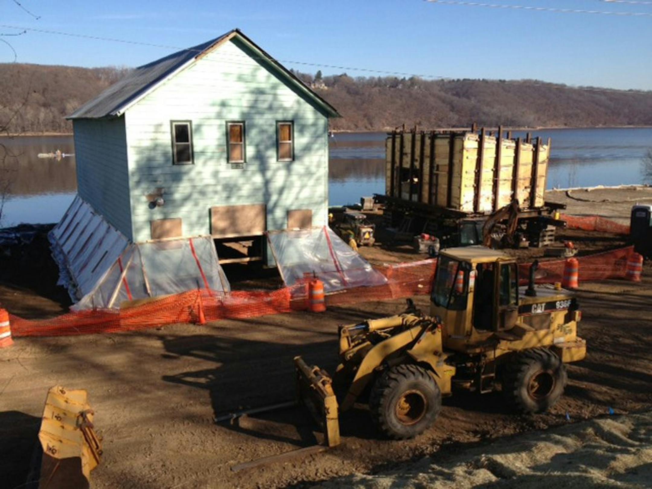 The rubblestone Shoddy Mill, right, remained wrapped like a Christmas present last week to prevent the 120-year-old building from collapsing during the move to its new home on the St. Croix River. The warehouse, left, was being lowered onto a foundation. Historians hope the green siding will be removed to exposed the original clapboard exterior.