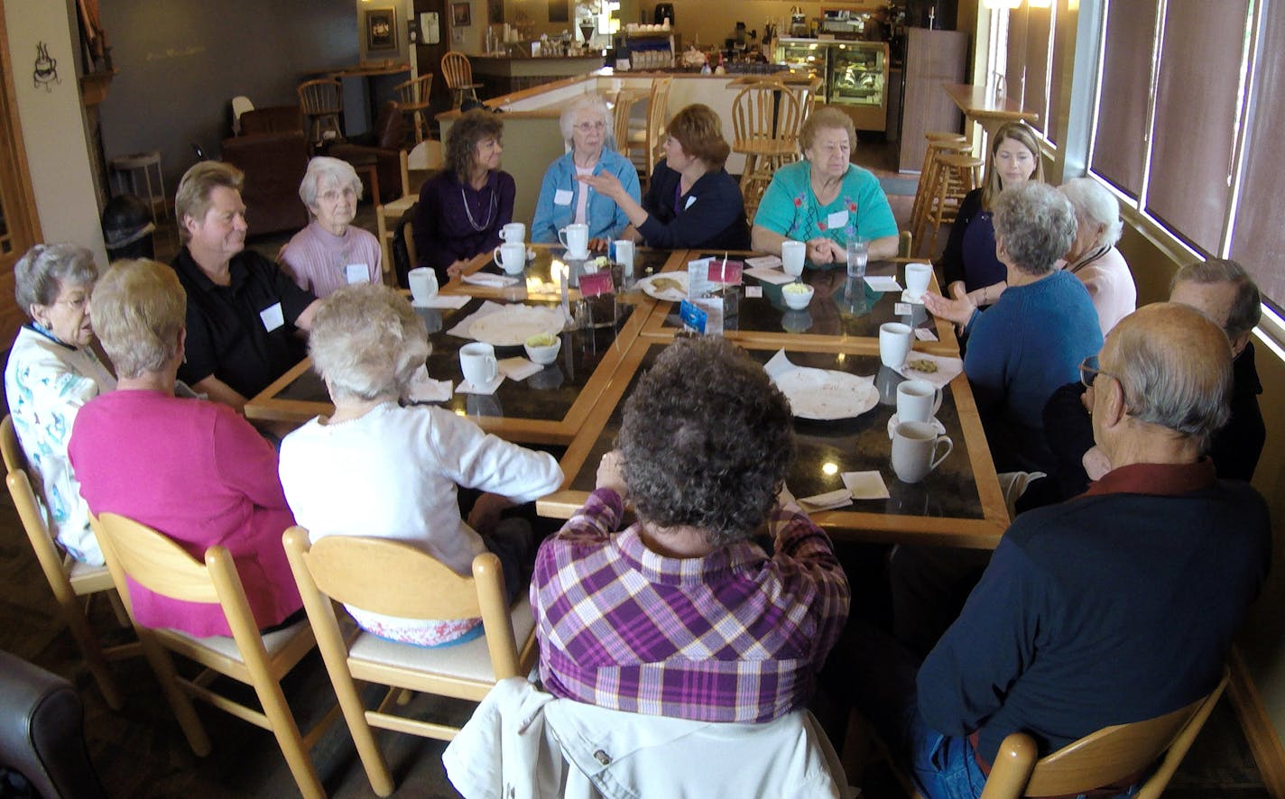 In this photo taken May 20, 2015 at Connections Cafe in Watertown, Wis., a group of people with dementia, their caregivers and officials from a local nursing home talk, drink coffee and eat cookies. The support and social group called "Memory Cafe" is part of the city's efforts to become a dementia friendly city. (AP Photo/Carrie Antlfinger) ORG XMIT: RPCA101