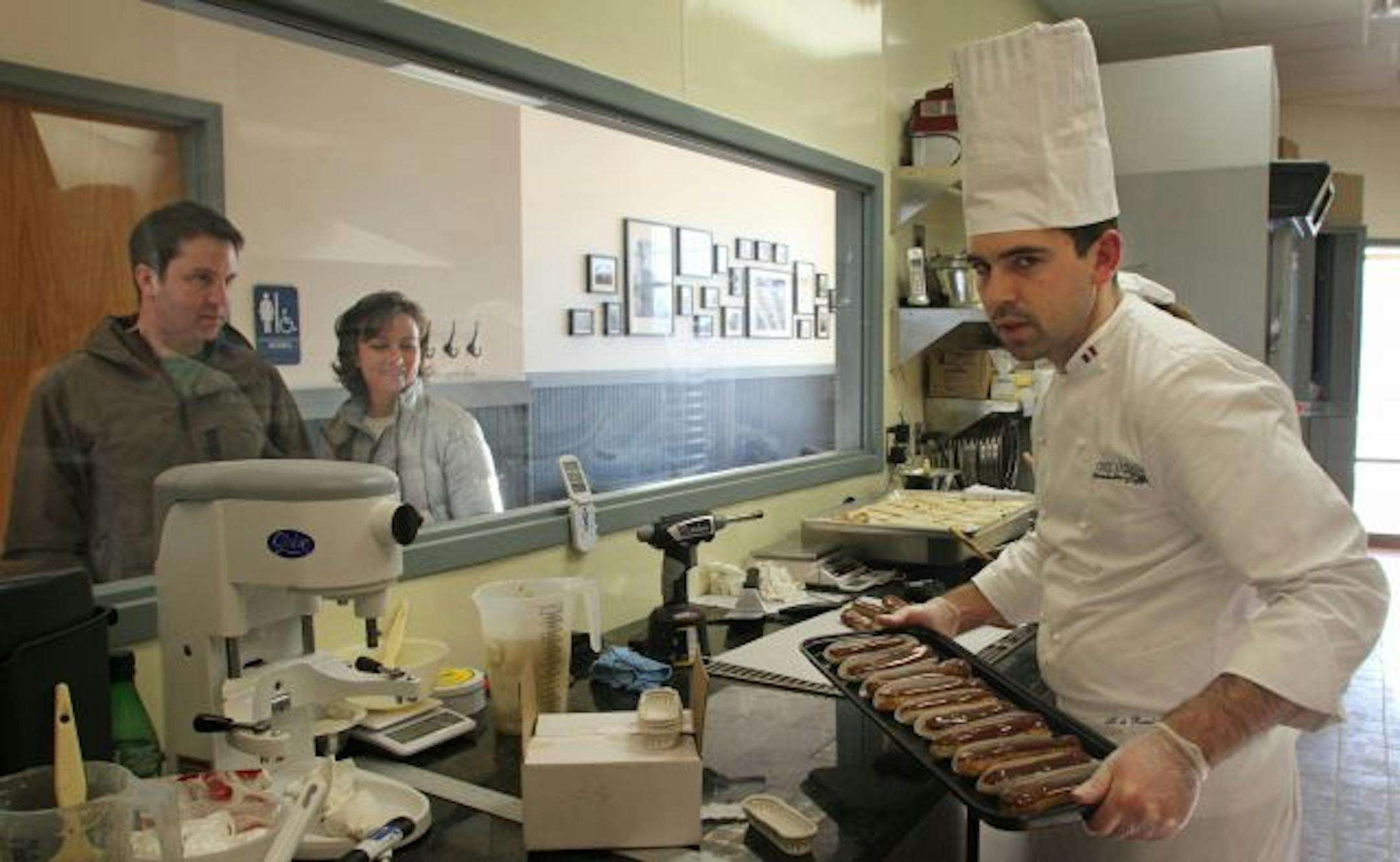 Customers Derik and Cathy Goodman watch Chez Arnaud pastry chef/owner Arnaud de Rambures prepare eclairs.