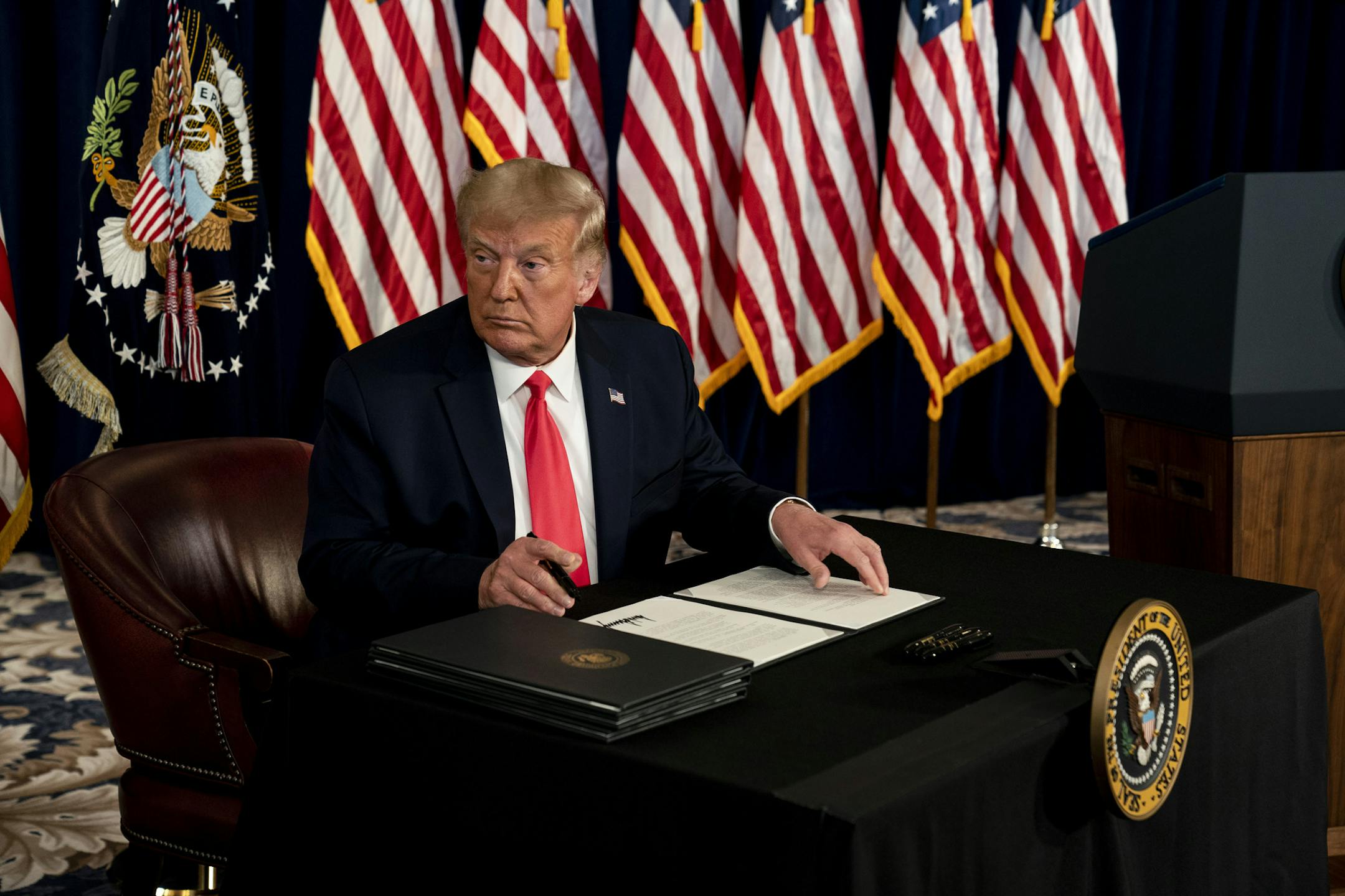 President Donald Trump signs an executive order related to coronavirus pandemic relief during a news conference at Trump National Golf Club in Bedminster, N.J., on Aug. 8, 2020. (Anna Moneymaker/The New York Times)