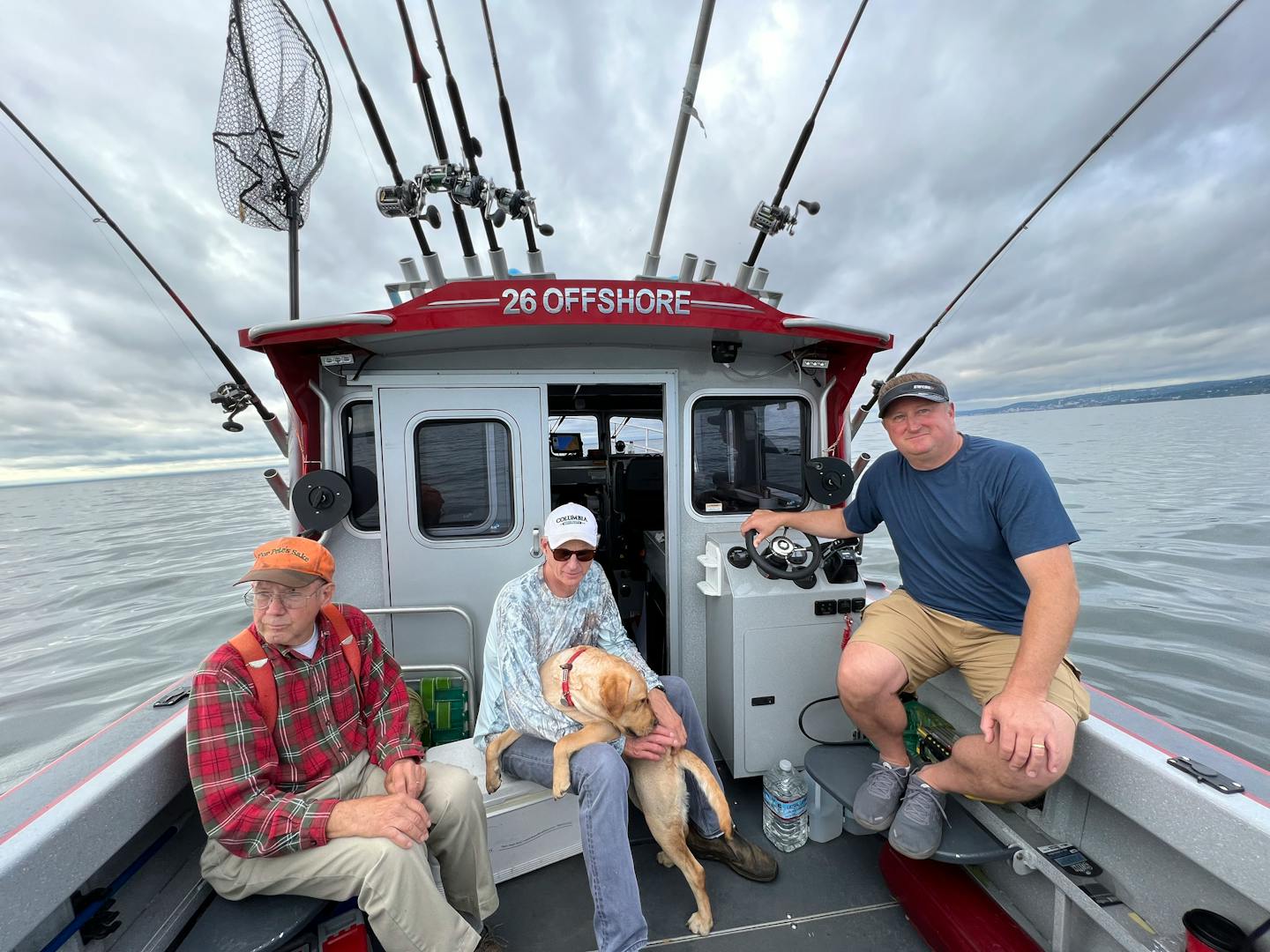 Pete Harris, left, of Grand Marais and Terry Arnesen and Mark Strelnieks of the Twin Cities are joined by Fetch, a yellow Labrador, on Arnesen's boat while trolling on Lake Superior near Duluth for lake trout and salmon, either coho or chinook.