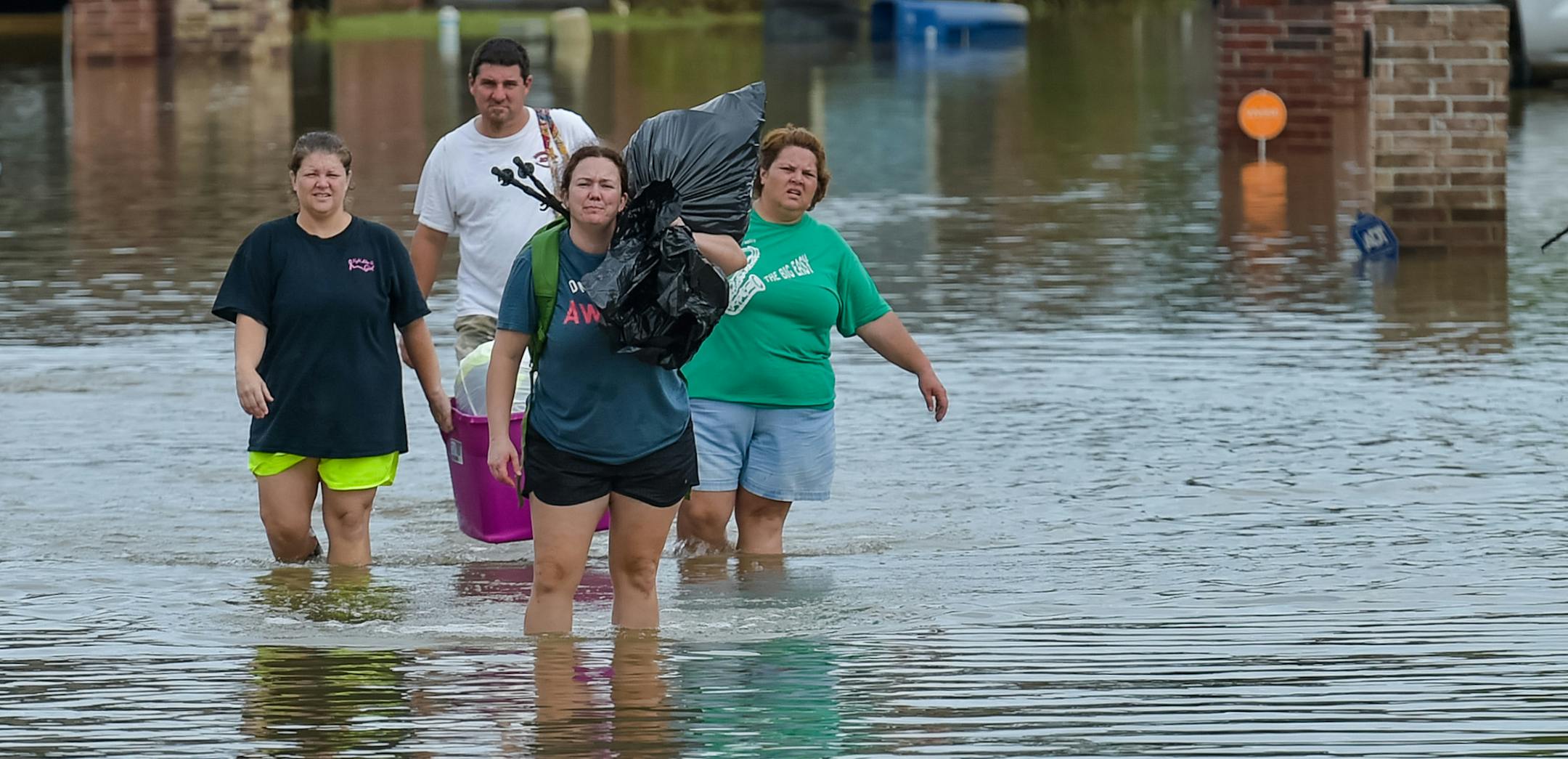 People wade in water near flood damaged homes in Highland Ridge Subdivision in Youngsville, La., Sunday, Aug. 14, 2016. Torrential rains swamped parts of southern Louisiana, causing widespread flooding. (Scott Clause/The Daily Advertiser via AP) ORG XMIT: MIN2016081508044807