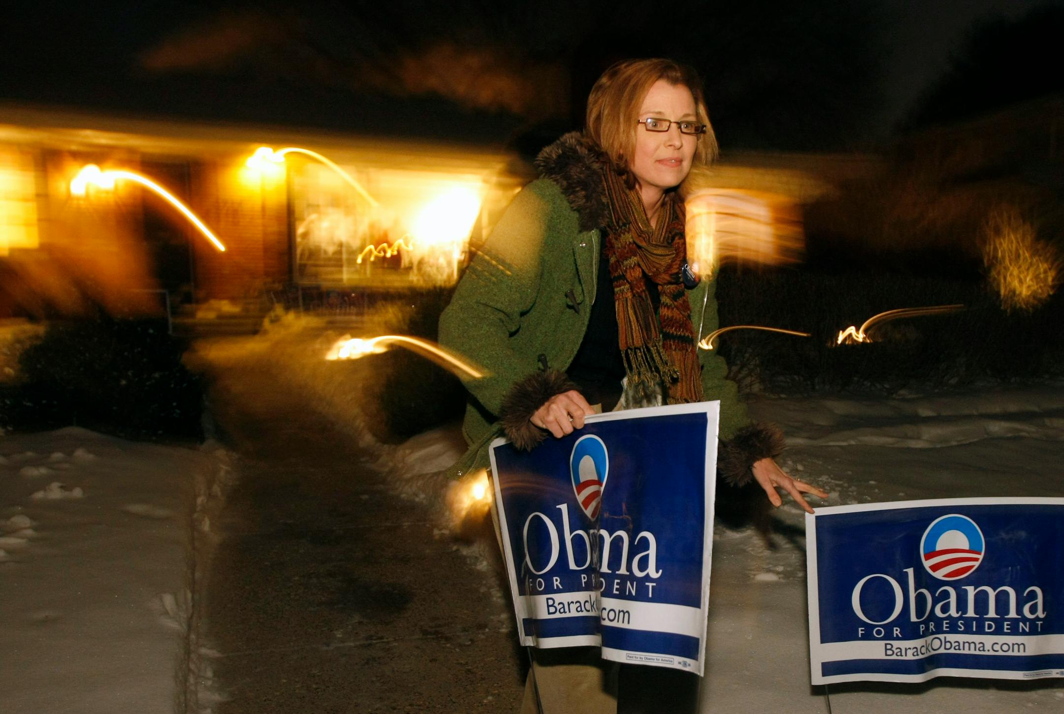 Laura Nisi places signs outside the home of Danielle Arlowe in Edina before a house party held to gather support for Barack Obama. Those in attendance were encouraged to take the lawn signs home at the end of the evening.