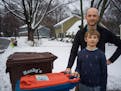 David Haeg and his 9-year-old son Winston take the organics bin to the curb for pickup in Minnetonka last Monday. Haeg is one of a number of Hennepin 