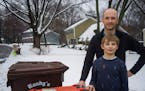David Haeg and his 9-year-old son Winston take the organics bin to the curb for pickup in Minnetonka last Monday. Haeg is one of a number of Hennepin 