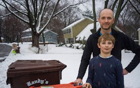 David Haeg and his 9-year-old son Winston take the organics bin to the curb for pickup in Minnetonka last Monday. Haeg is one of a number of Hennepin 