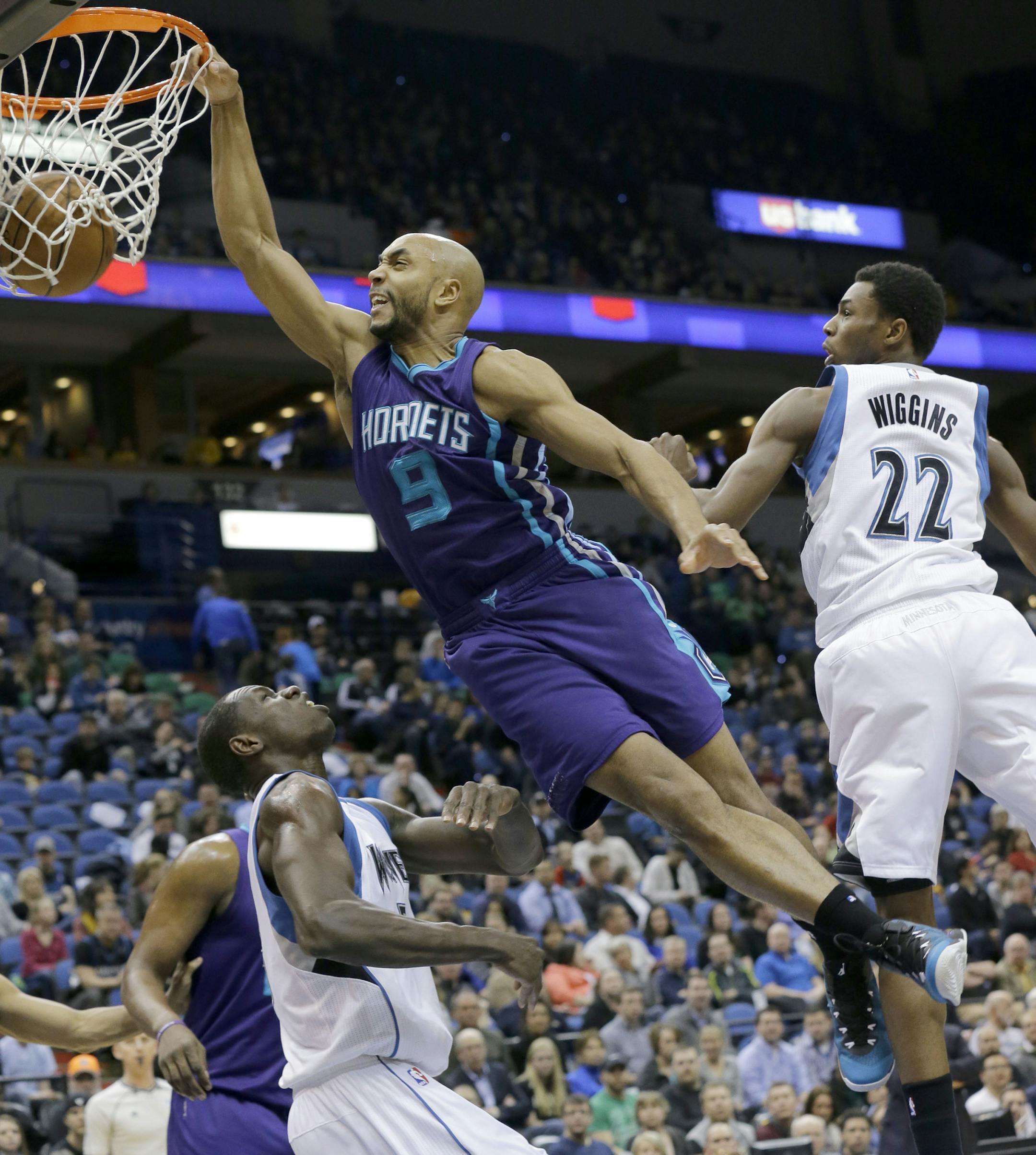 Charlotte Hornets guard Gerald Henderson (9) dunks against Minnesota Timberwolves forward Andrew Wiggins (22) and Timberwolves center Gorgui Dieng, left, of Senegal, during the first half of an NBA basketball game in Minneapolis, Sunday, March 22, 2015. (AP Photo/Ann Heisenfelt)