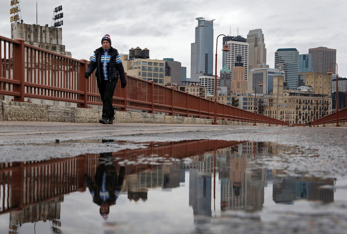 A pedestrian walked bundled in winter gear across the Stone Arch Bridge as heavy storm clouds loomed over downtown Minneapolis ahead of this weekend's snow storm. ] ANTHONY SOUFFLE &#xef; anthony.souffle@startribune.com The Twin Cities saw a wintery mix of rain and sleet just ahead of this weekend's megastorm expected to dump about 8 inches of snow on the area Friday, April 13, 2018 in Minneapolis.