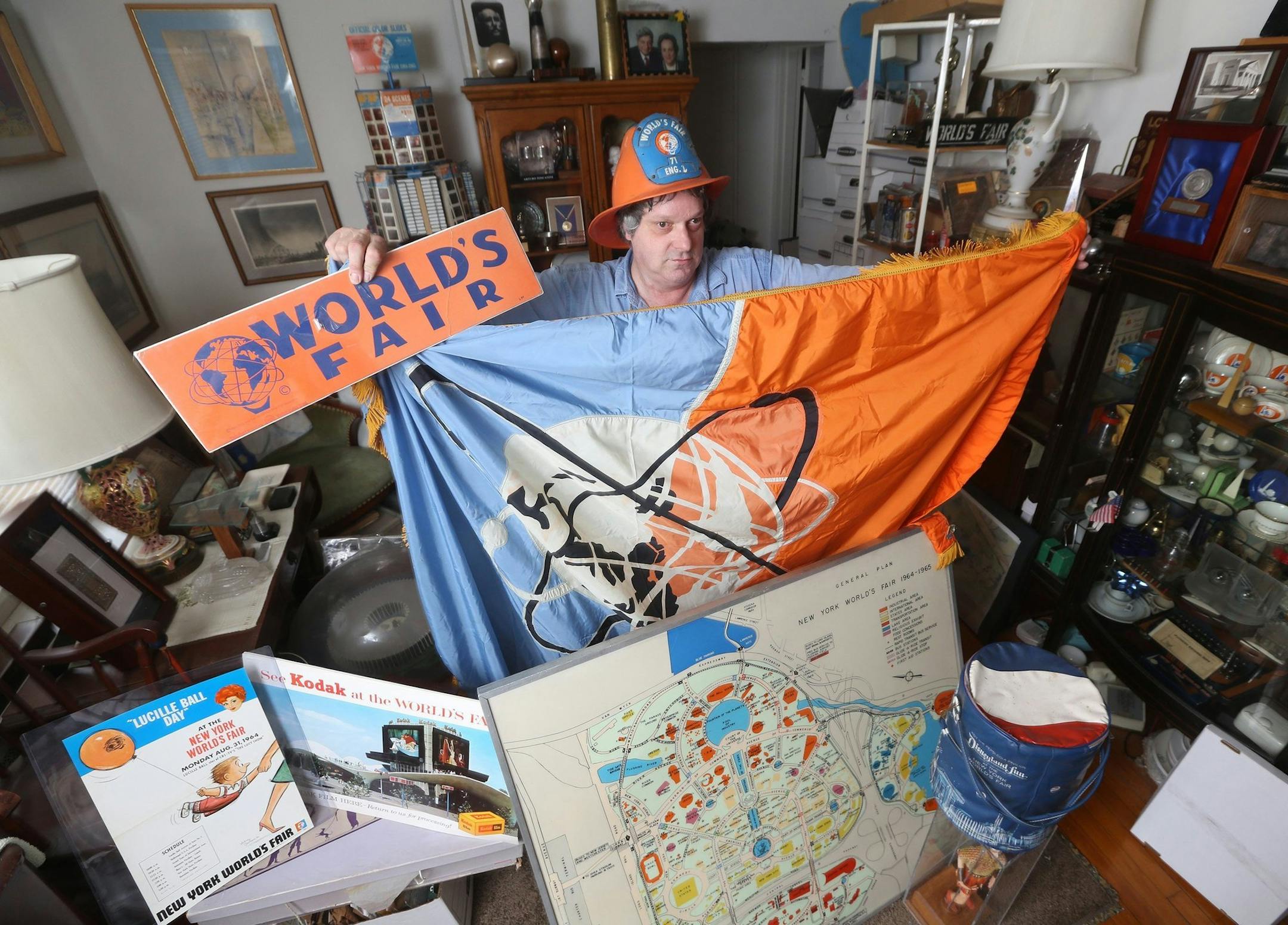 John Riccardelli shows off his huge collection of World's Fair items that are kept in his apartment in New Milford, N.J., Monday, April 14, 2014. Here, he wears a World's Fair fireman's helmet, and holds up a World's Fair flag that hung behind the desk of Robert Moses, as well as posters and maps of the Fair. (Chris Pedota/The Record/MCT) ORG XMIT: 1152121
