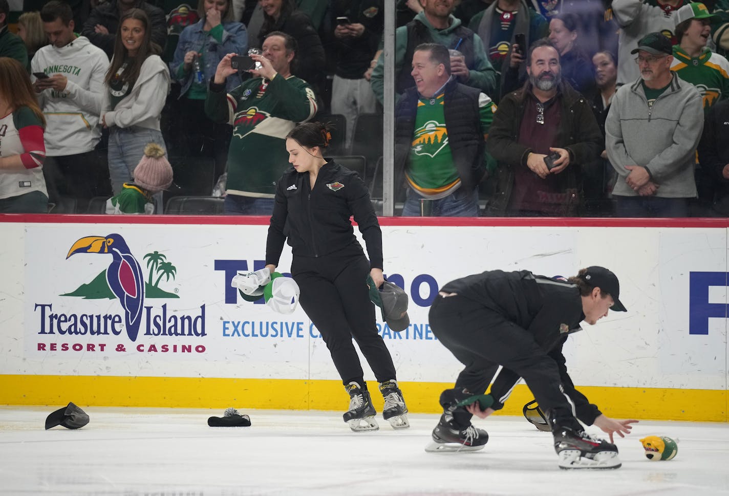 The ice crew cleans up the hats after fans threw hats on the ice to celebrate Minnesota Wild center Joel Eriksson Ek's hat trick at the X.