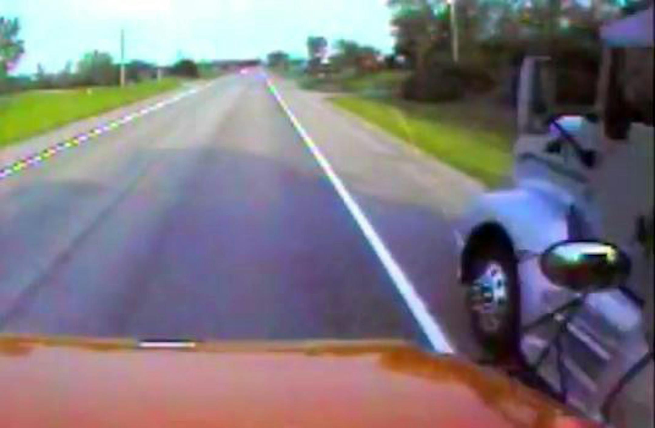 This screen grab from the bus video shows the semi roaring by the stopped bus, on the shoulder of the highway.