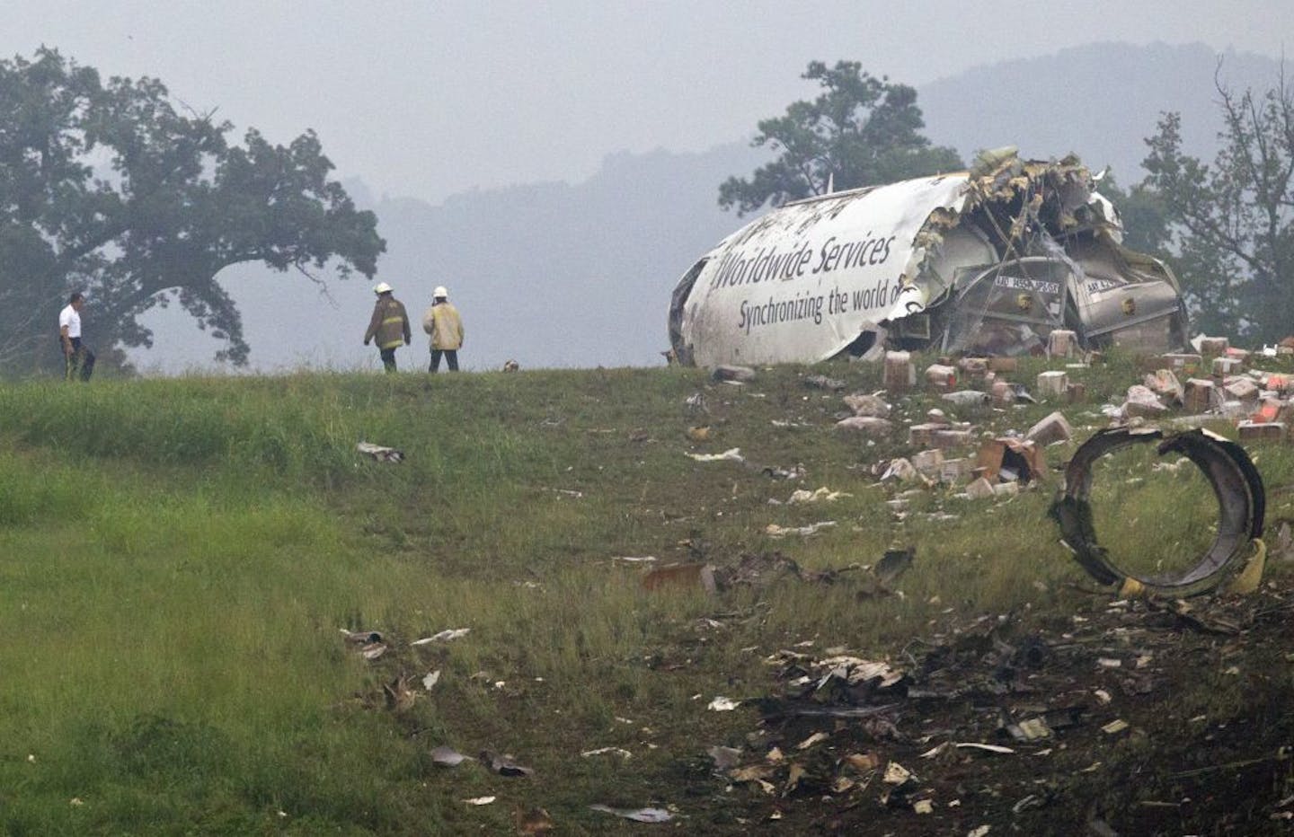 Fire crews investigate where a UPS cargo plane lies on a hill at Birmingham-Shuttlesworth International Airport after crashing on approach, Wednesday, Aug. 14, 2013, in Birmingham, Ala.