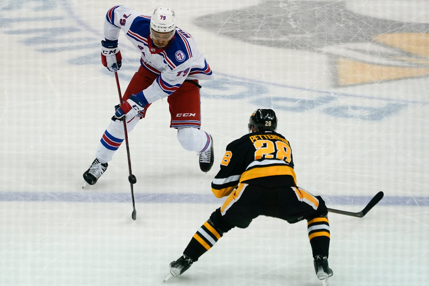 New York Rangers' K'Andre Miller (79) tries to bring the puck past defending Pittsburgh Penguins' Marcus Pettersson (28) during the third period of an NHL hockey game, Saturday, Feb. 26, 2022, in Pittsburgh. The Pittsburgh Penguins won 1-0. (AP Photo/Keith Srakocic)