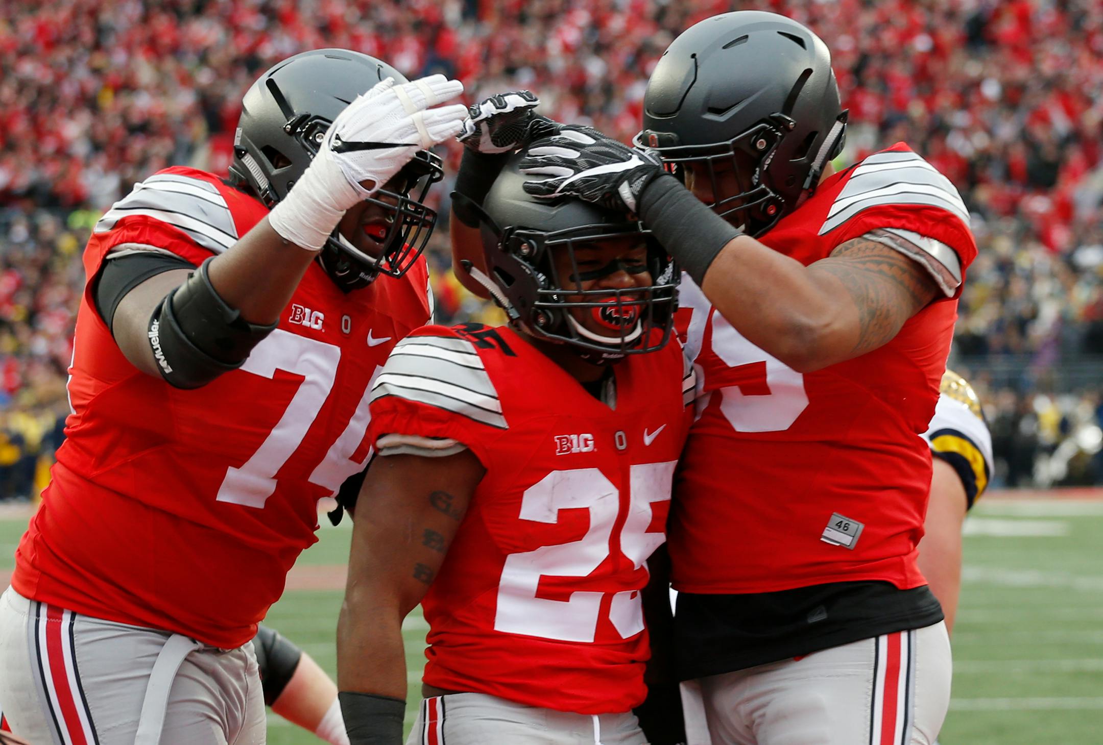 FILE - In this Nov. 26, 2016, file photo, Ohio State running back Mike Weber, center, celebrates his touchdown against Michigan with teammates Jamarco Jones, left, and Luke Farrell during the second half of an NCAA college football game in Columbus, Ohio. Alabama will play Washington and Ohio State is set to face Clemson in the College Football Playoff semifinals, announced Sunday, Dec. 4. (AP Photo/Jay LaPrete)