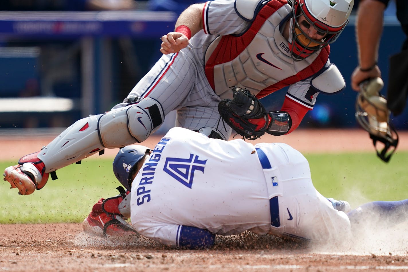 Toronto Blue Jays' George Springer (4) dives for home plate and collides with Minnesota Twins catcher Ryan Jeffers (27) during the fifth inning of a baseball game in Toronto, Saturday, June 10, 2023. (Arlyn McAdorey/The Canadian Press via AP)