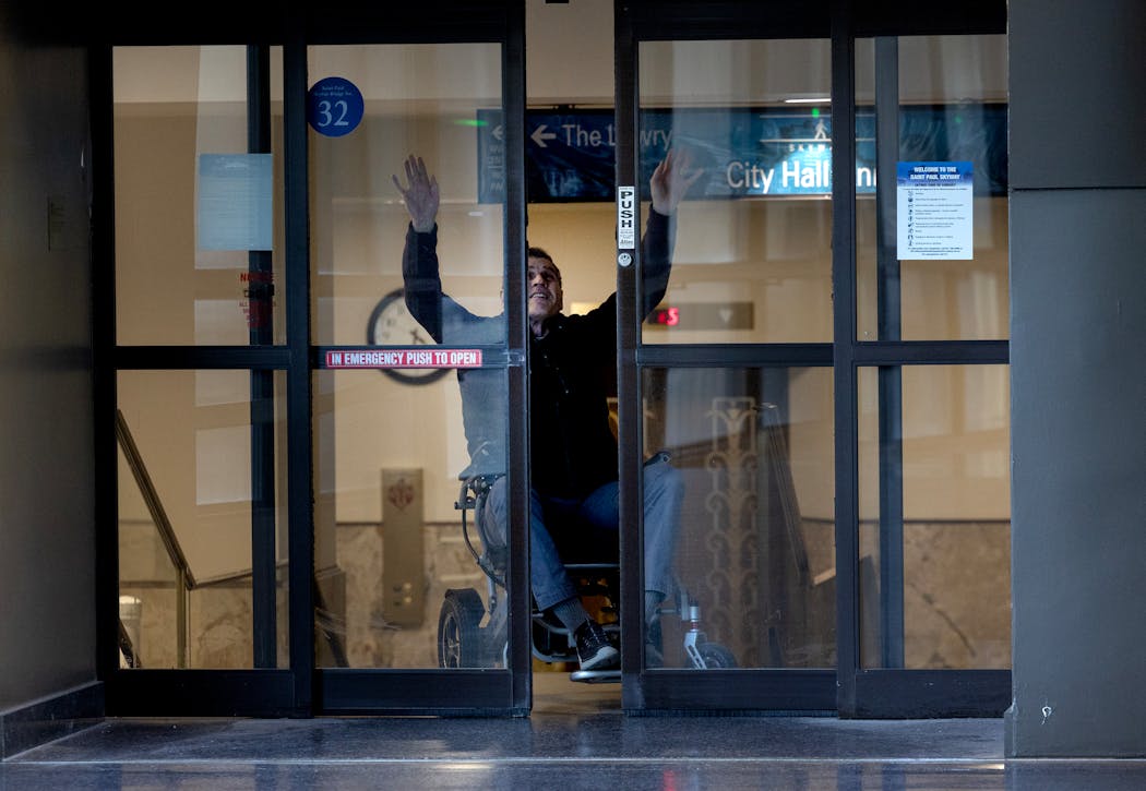 Star Tribune reporter James Walsh waves his hands in an effort to trigger a sensor that open the door to the skyway to enter St. Paul City Hall last month. City leaders have promised to make the historic building more accessible.