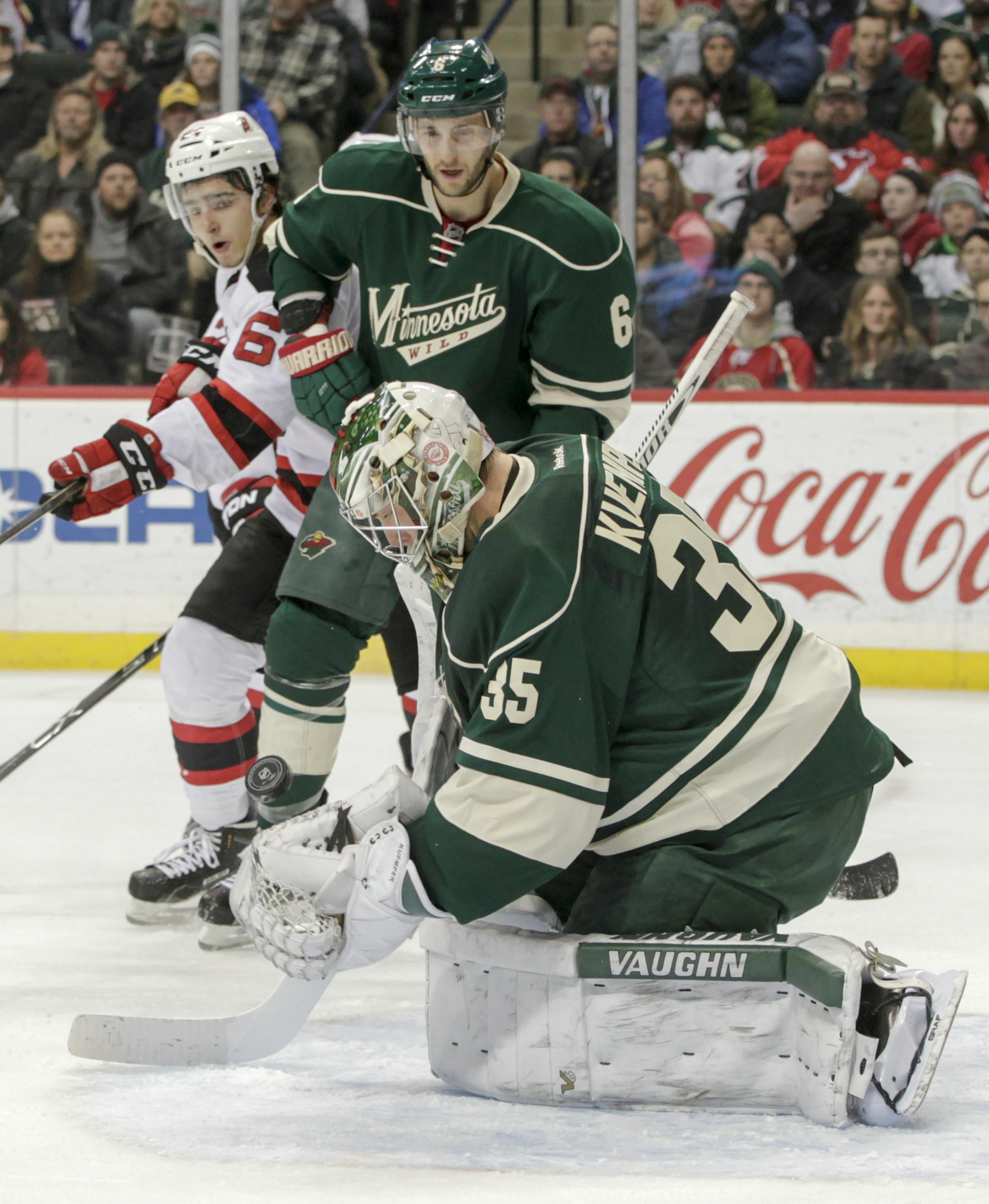 Minnesota Wild goalie Darcy Kuemper (35) makes a save as teammate Marco Scandella (6) and the New Jersey Devils' Travis Zajac (19) and Joseph Blandisi (64) look on during the second period of an NHL hockey game, Sunday, Jan. 10, 2016, in St. Paul, Minn. The Devils won 2-1. (AP Photo/Paul Battaglia)