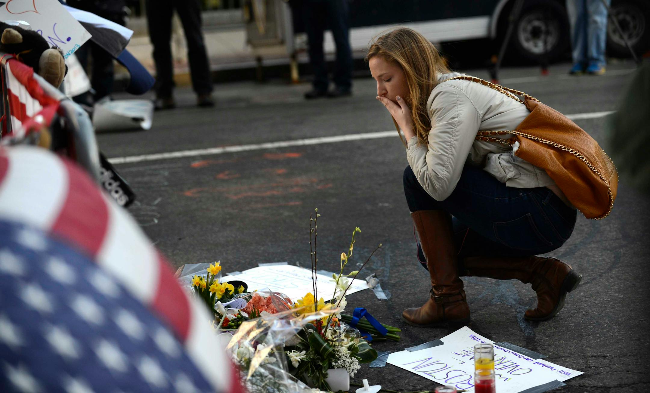 Margret Schulz kneels at a makeshift memorial on Boylston Street in Boston.