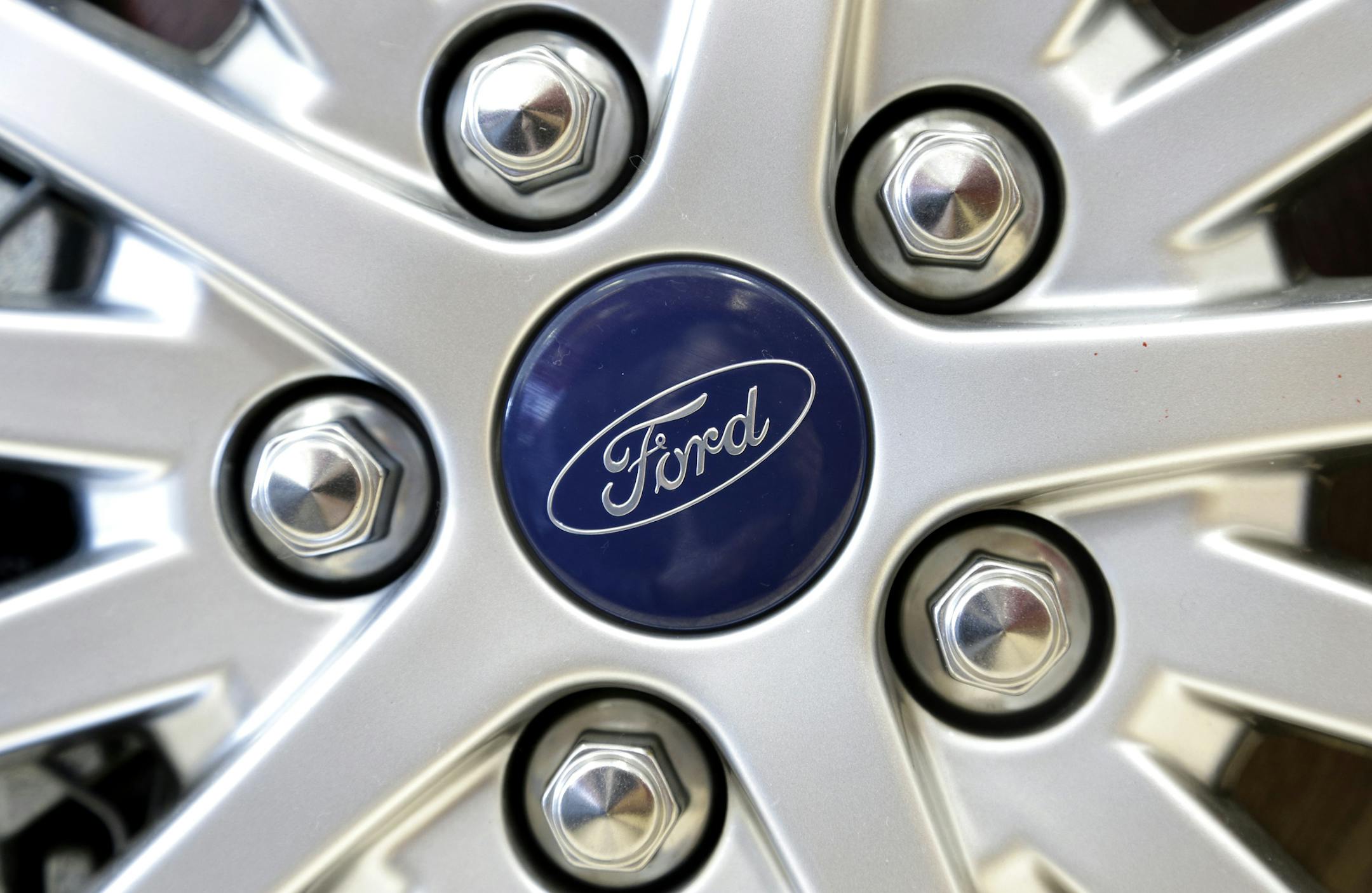A Ford emblem is attached to the wheel of a sedan at a Ford dealership in, Norwood, Mass.