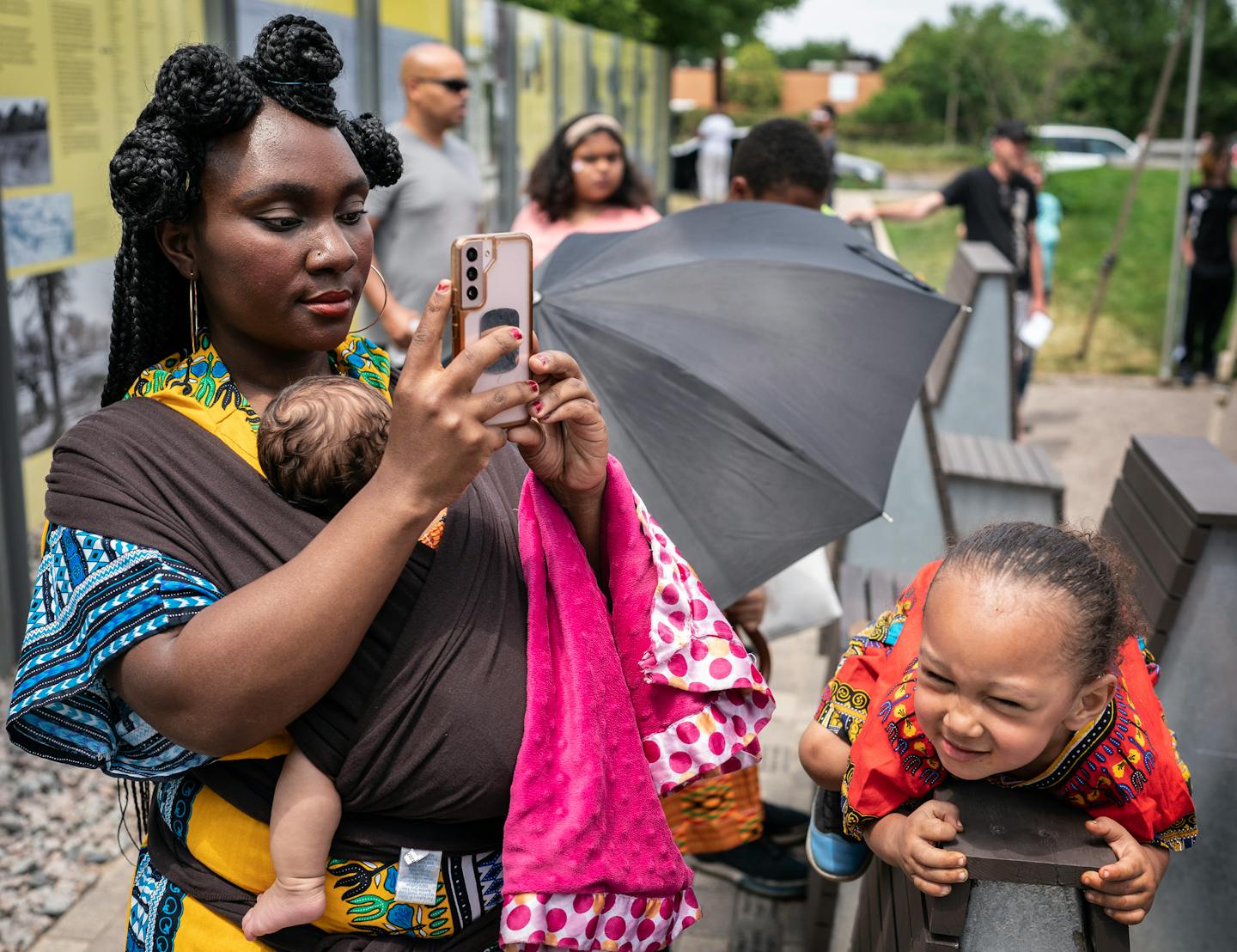 Jasmine Amacher, holding her 2-month-old daughter Elora, and son Roman, looked at the a wall displaying the history of the Rondo neighborhood at the J