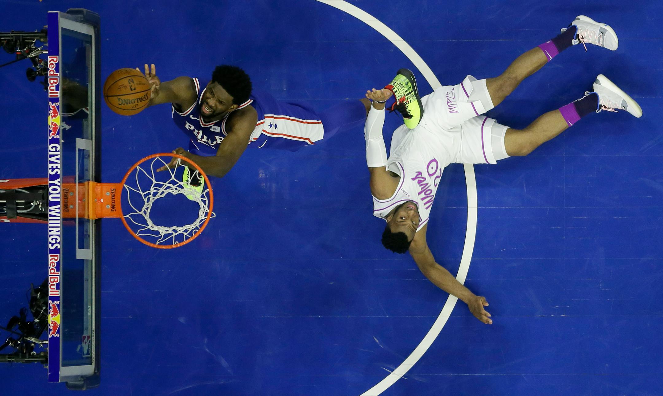 Joel Embiid, left, goes up for a shot off the Timberwolves' Josh Okogie during the first half