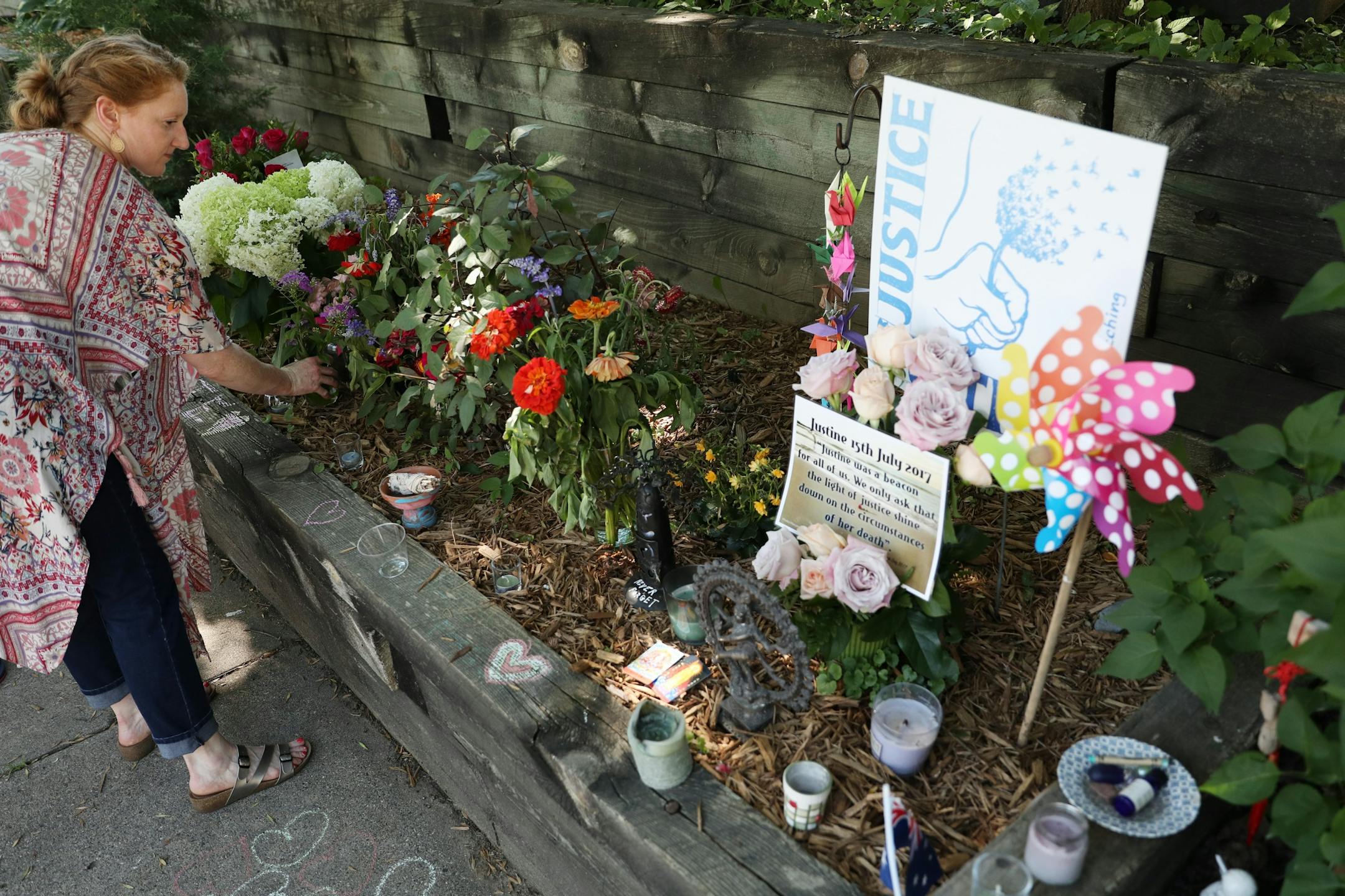 Sara Crawford arranged flowers, candles, signs, and trinkets that made up a memorial for Justine Ruszczyk Damond near the ally where she was killed on the one year anniversary of her death.