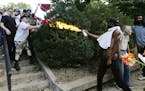 A counter demonstrator uses a lighted spray can against a white nationalist demonstrator at the entrance to Lee Park in Charlottesville, Va., Saturday