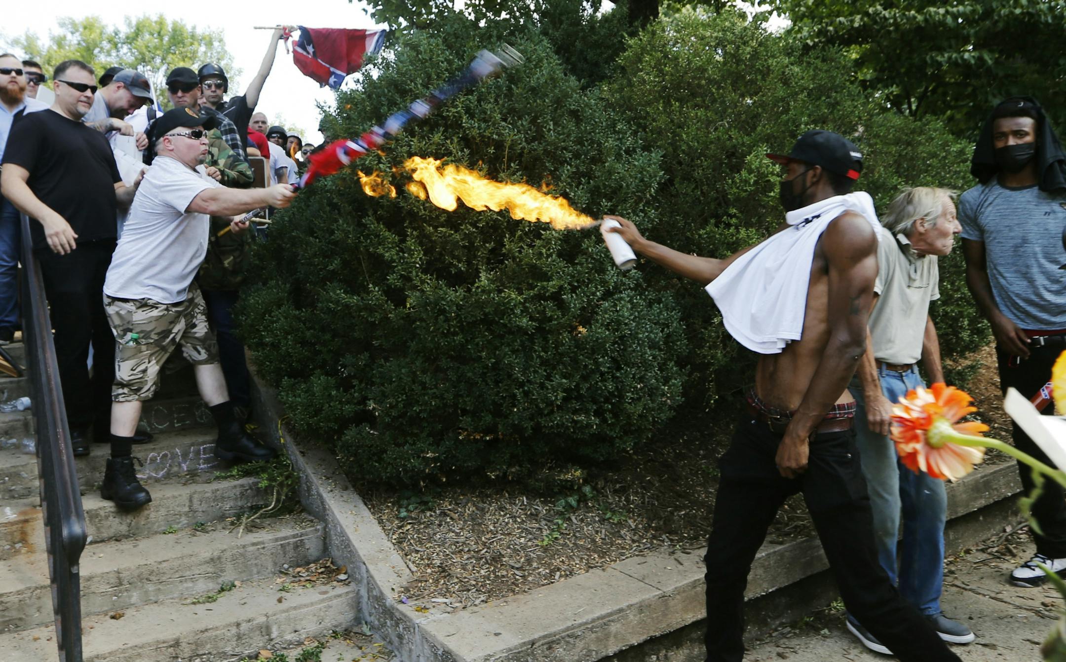 A counter demonstrator uses a lighted spray can against a white nationalist demonstrator at the entrance to Lee Park in Charlottesville, Va., Saturday, Aug. 12, 2017. Gov. Terry McAuliffe declared a state of emergency and police dressed in riot gear ordered people to disperse after chaotic violent clashes between white nationalists and counter protestors.