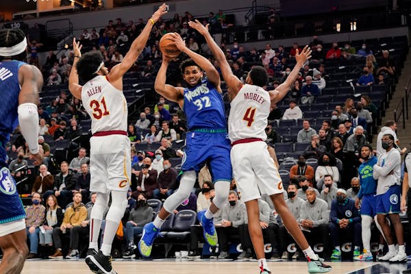 Timberwolves center Karl-Anthony Towns is boxed in by Cavaliers center Jarrett Allen and forward Evan Mobley