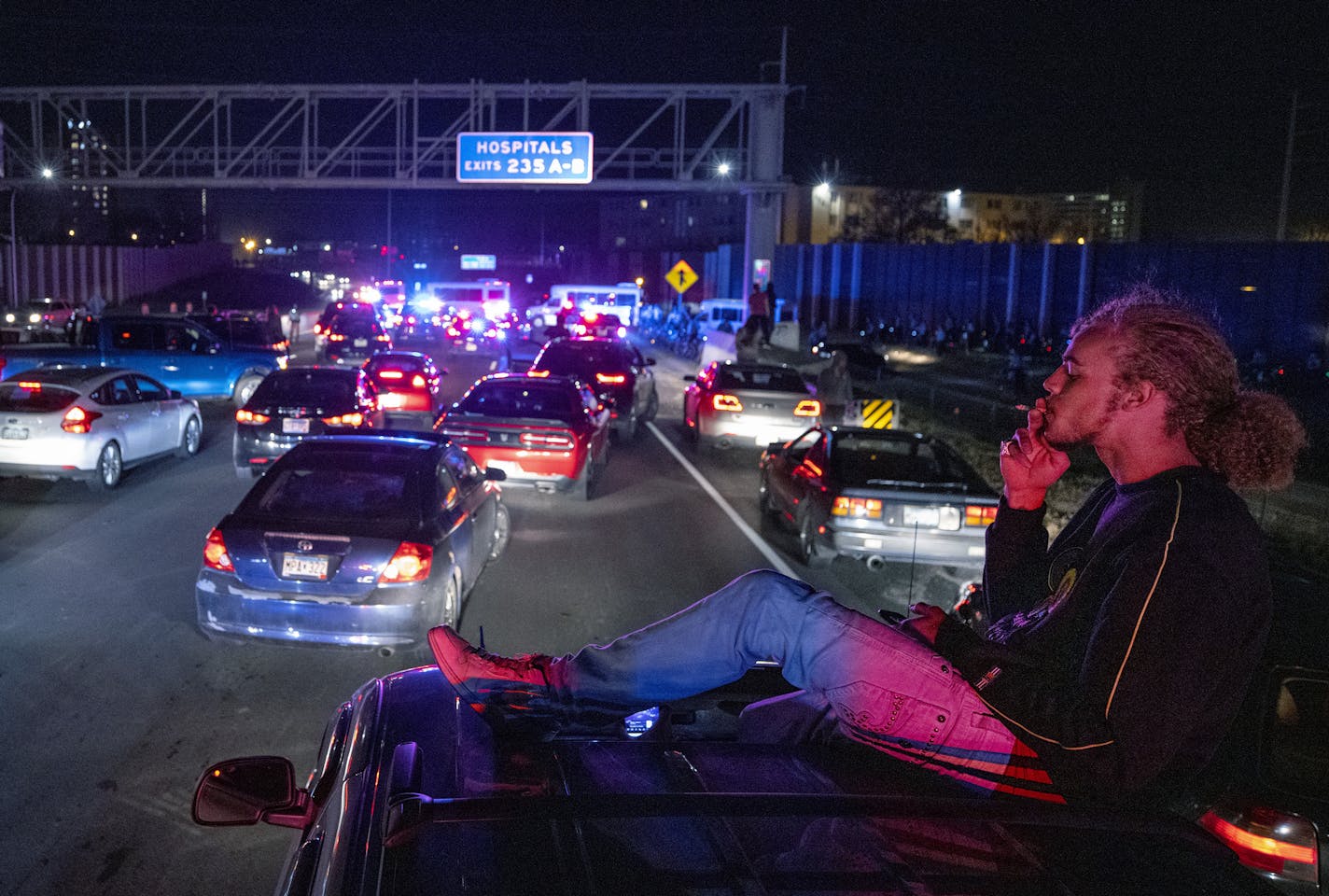 Payton Wood, 21, of St. Paul, Minn., has a cigarette on the roof of his friends SUV while stopped on I-94 Wednesday, Nov. 4, 2020 in Minneapolis. Police shut down part of the Interstate after protesters marched on it.(Carlos Gonzalez/Star Tribune via AP)