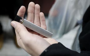 A man displays his Juul electronic cigarette while shopping at a convenience store in Hoboken, N.J., Thursday, Dec. 20, 2018. Altria, one of the world