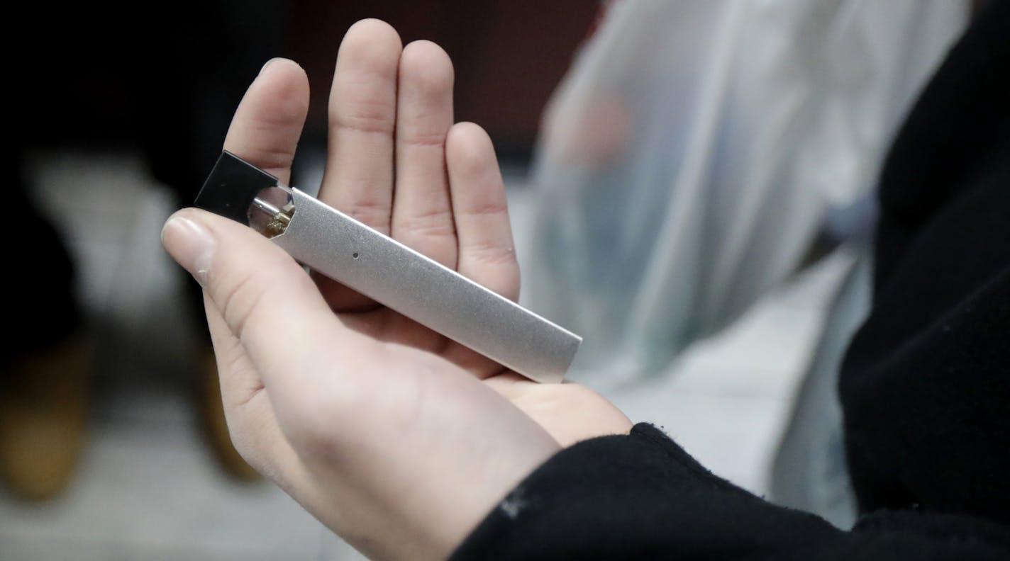 A man displays his Juul electronic cigarette while shopping at a convenience store in Hoboken, N.J., Thursday, Dec. 20, 2018. Altria, one of the world's biggest tobacco companies, is spending nearly $13 billion to buy a huge stake in the vape company Juul as cigarette use continues to decline. (AP Photo/Julio Cortez)