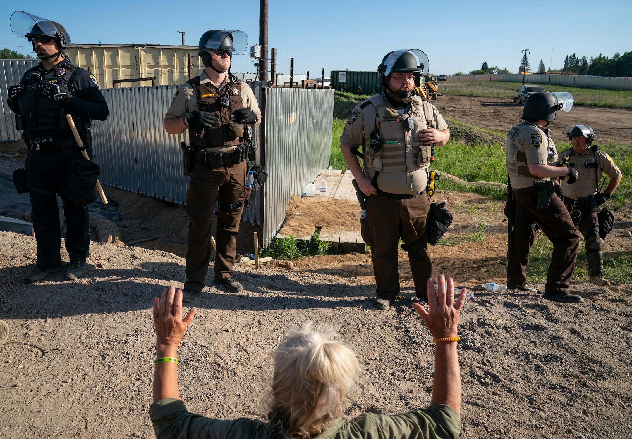 Law enforcement agents formed a line in front of a wall of protestors who sat just in front of a locked gate at an Enbridge pump station on Monday.