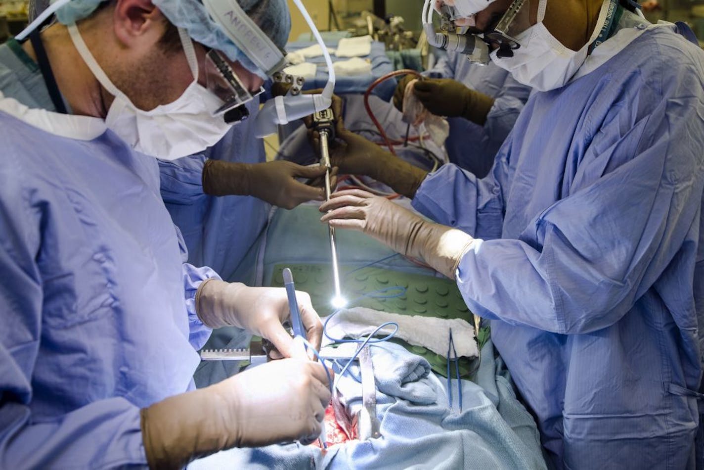 FILE - In this Tuesday, Jan. 23, 2018 file photo, a surgeon directs a special camera to be able to view his patient's cancer tumor on monitors while performing surgery at a hospital in Philadelphia. As the COVID-19 coronavirus spreads, many cancer surgeries are being delayed, stent procedures for clogged arteries have been pushed back and infertility specialists were asked to postpone helping patients get pregnant. In March 2020, doctors in virtually every field are scrambling to alter care.