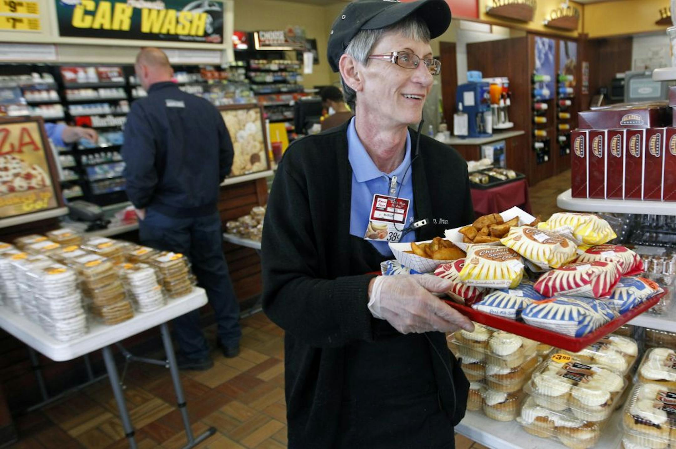 At the Kwik Trip store, Marge Weber, an employee of three years, brings out some hot sandwiches and eats to the display case.