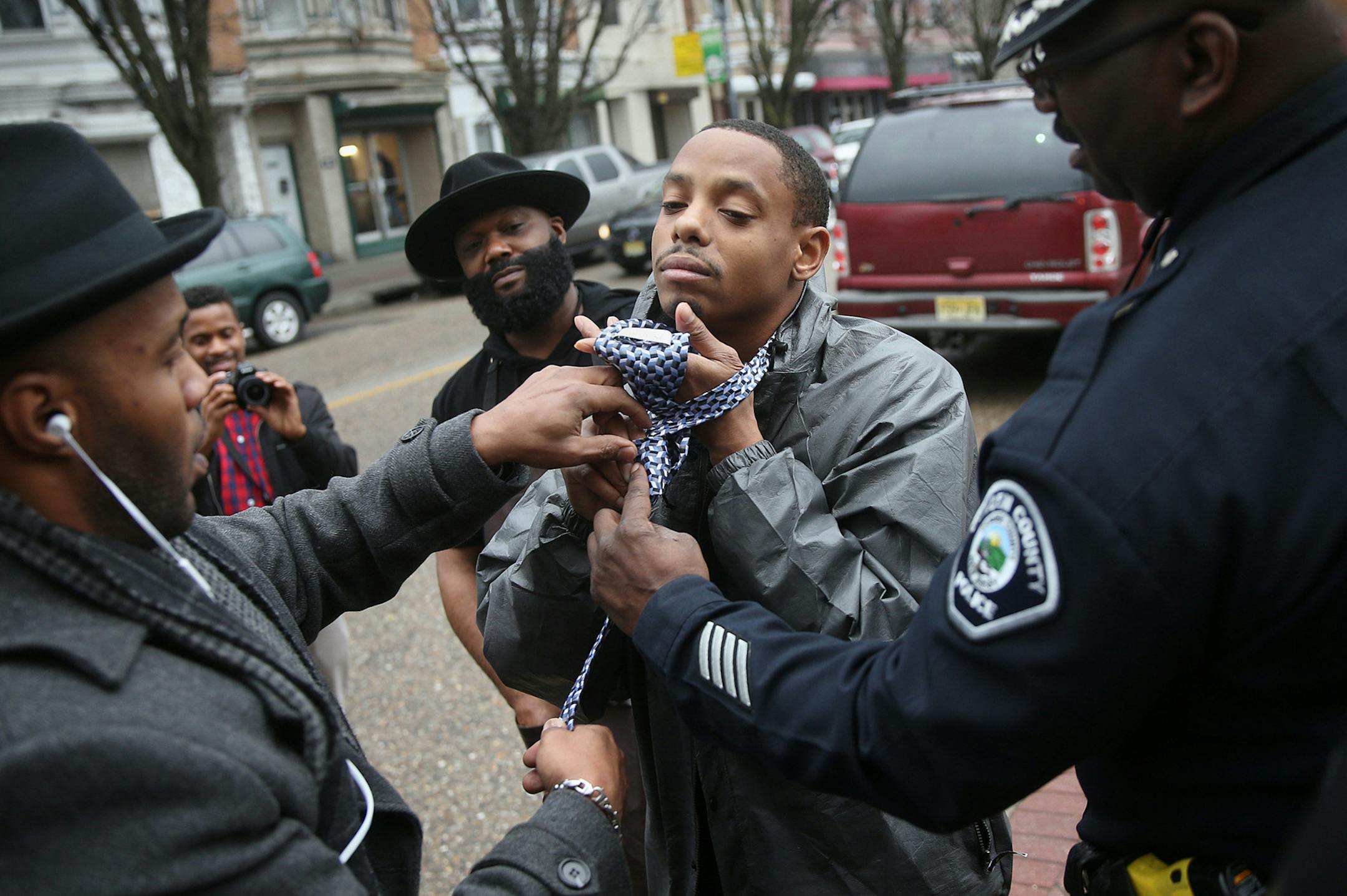 Chris Cream, left, and Camden County Police Lt. Zsakhiem James, right, show Albert Reeder how to tie a tie while giving out free suits and ties to men in Camden, N.J., on Saturday, Feb. 24, 2018. (Tim Tai/Philadelphia Inquirer/TNS)